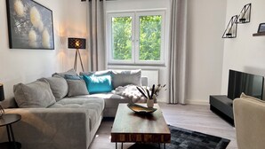 Ein modernes Wohnzimmer mit Sofa, Couchtisch und Fernseher.