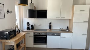 Eine moderne Küche mit weißen Schränken, Backofen, Geschirrspüler und Kaffeemaschine.