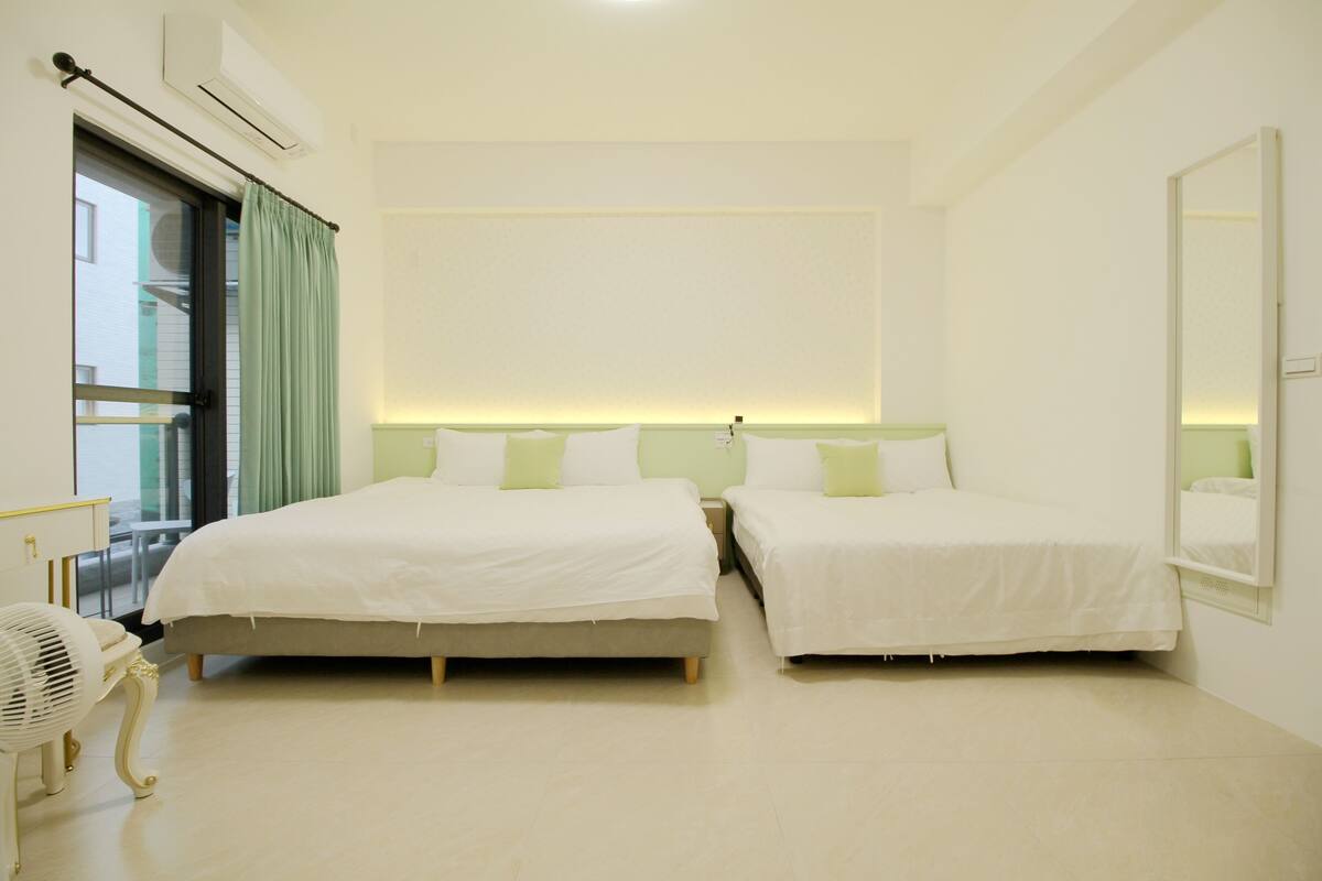 A hotel room with two beds, a large mirror, and a fan.