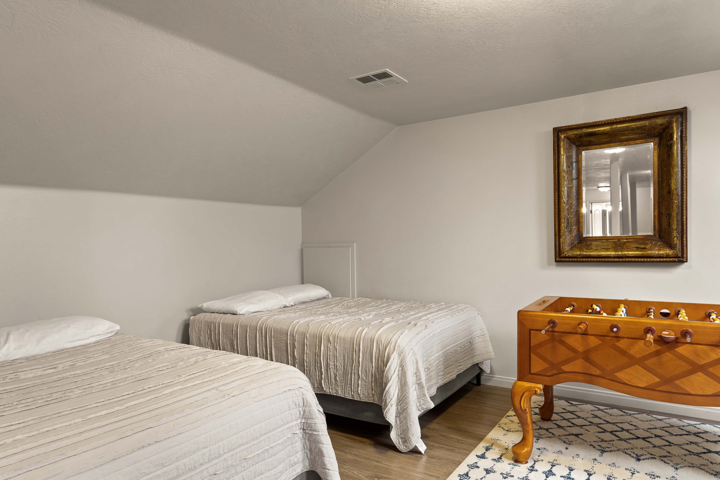 A bedroom with two beds, a wooden dresser, and a mirror on the wall.