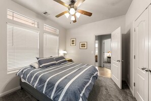 A bedroom with a bed, a ceiling fan, and a door leading to another room. - Family Oasis with Pool, Spa & Twist Slide - Minutes from St. George (Washington)