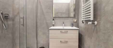A modern bathroom with a glass shower enclosure, a sink with a mirror, and a towel rack.