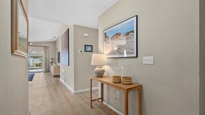 A hallway with a wooden console table, a lamp, and framed artwork on the walls. - Charming House with Heated Pool (Bradenton)