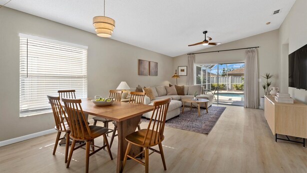A spacious living area with a dining table, chairs, a sofa, and a ceiling fan. - Charming House with Heated Pool (Bradenton)
