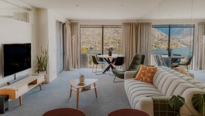 Een moderne woonkamer met een flatscreen-tv, een bank, een salontafel en een eethoek met een tafel en stoelen.