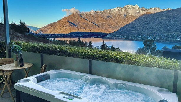 Een bubbelbad met uitzicht op een meer en bergen.