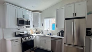 Una cocina moderna con armarios blancos, electrodomésticos de acero inoxidable y una estufa negra.