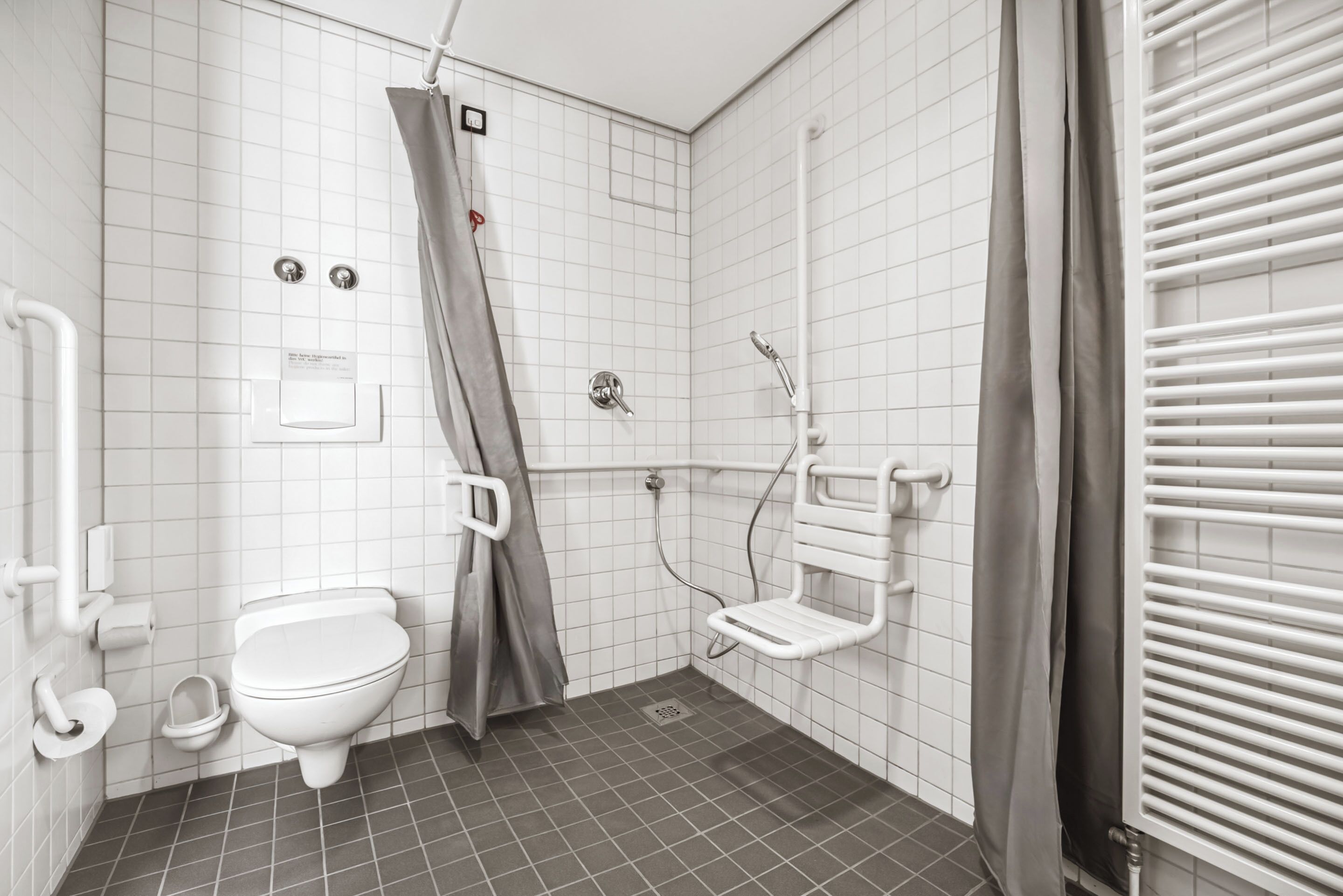 A bathroom with a white toilet, a shower with a grab bar, and a white sink.