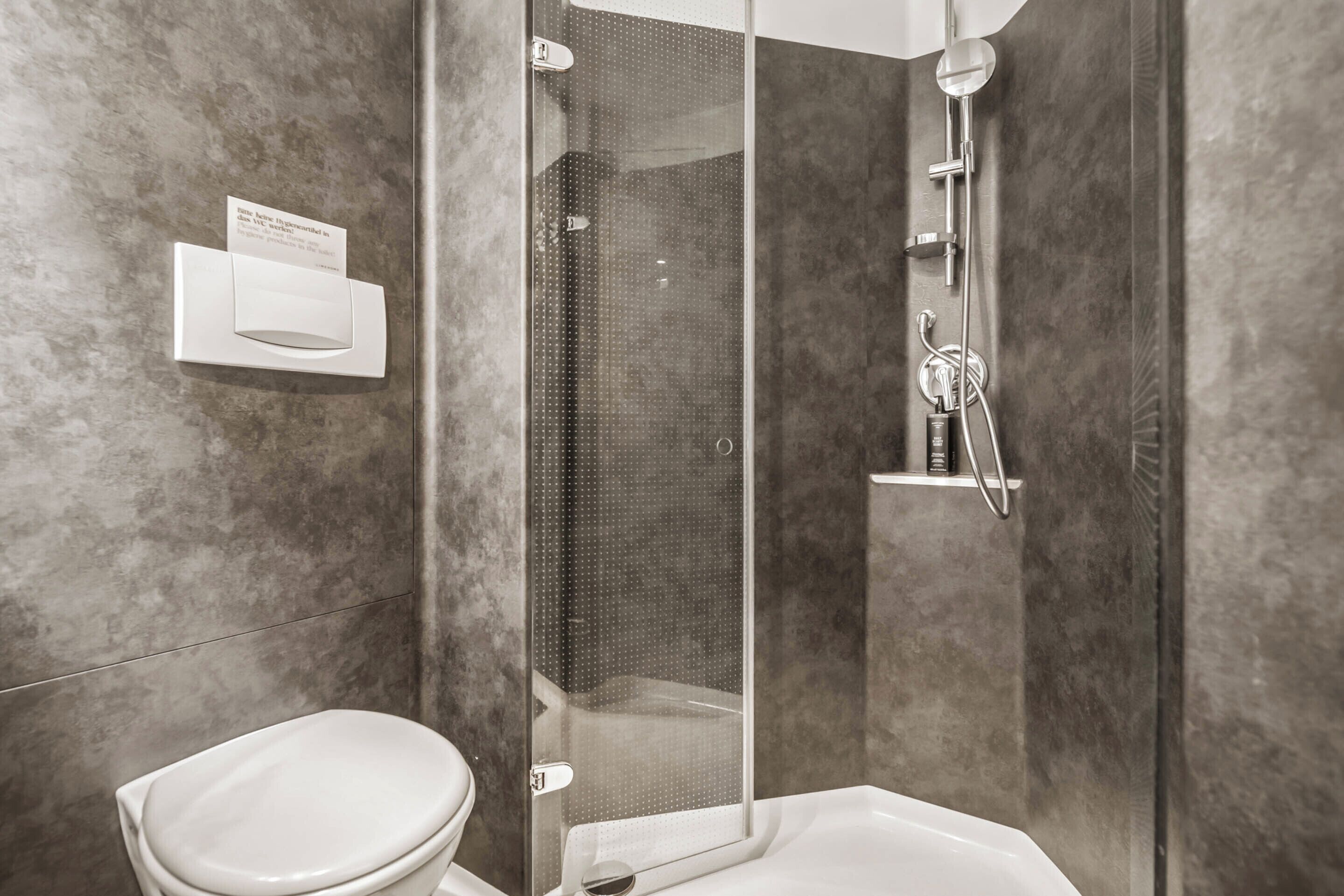 Ein modernes Badezimmer mit Toilette, einer gläsernen Dusche und einem integrierten Waschbecken.