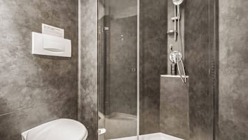 A modern bathroom with a toilet, a glass-enclosed shower, and a built-in sink.