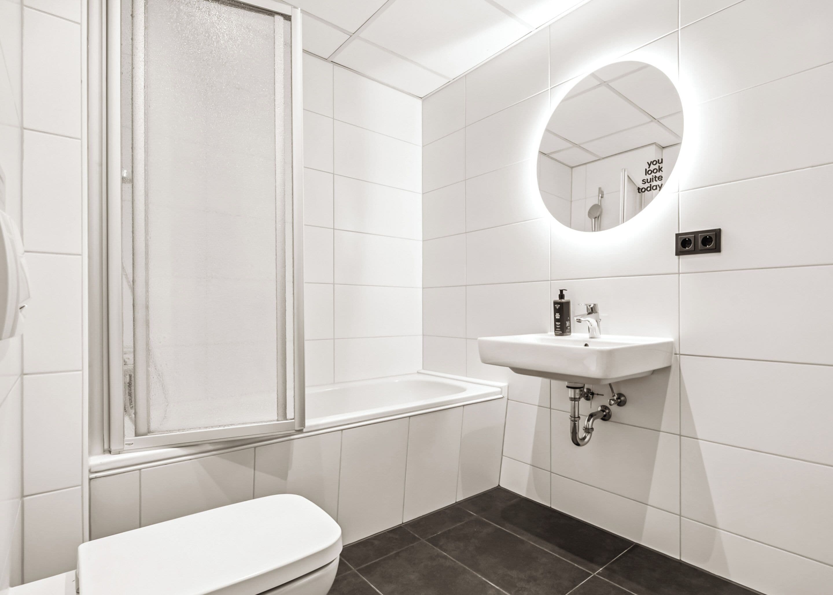 Une salle de bain moderne équipée de toilettes, d’un lavabo et d’une douche.