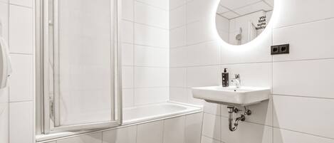 A modern bathroom with a toilet, a sink, and a shower.