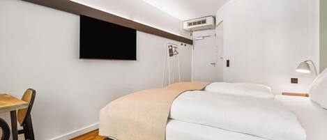 Una habitación de hotel moderna con una cama, un escritorio y un televisor fijado a la pared.