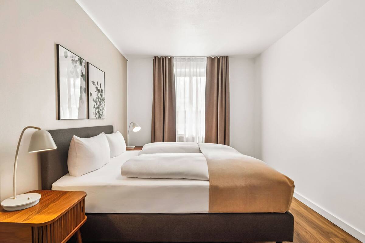 Een moderne hotelkamer met een groot bed, een nachtkastje met een lamp en kunst aan de muur.
