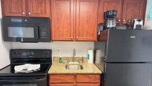 A kitchen with wooden cabinets, a black microwave, a Frigidaire oven, a sink, a coffee maker, and a Hotpoint refrigerator. - Amazing views - Kings size Ocean front Camelot 715 (Myrtle Beach)