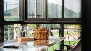 A wicker basket on a table with two wine glasses and a candle holder. - Jigeum Yeosu Ocean View Pension (Yeosu)