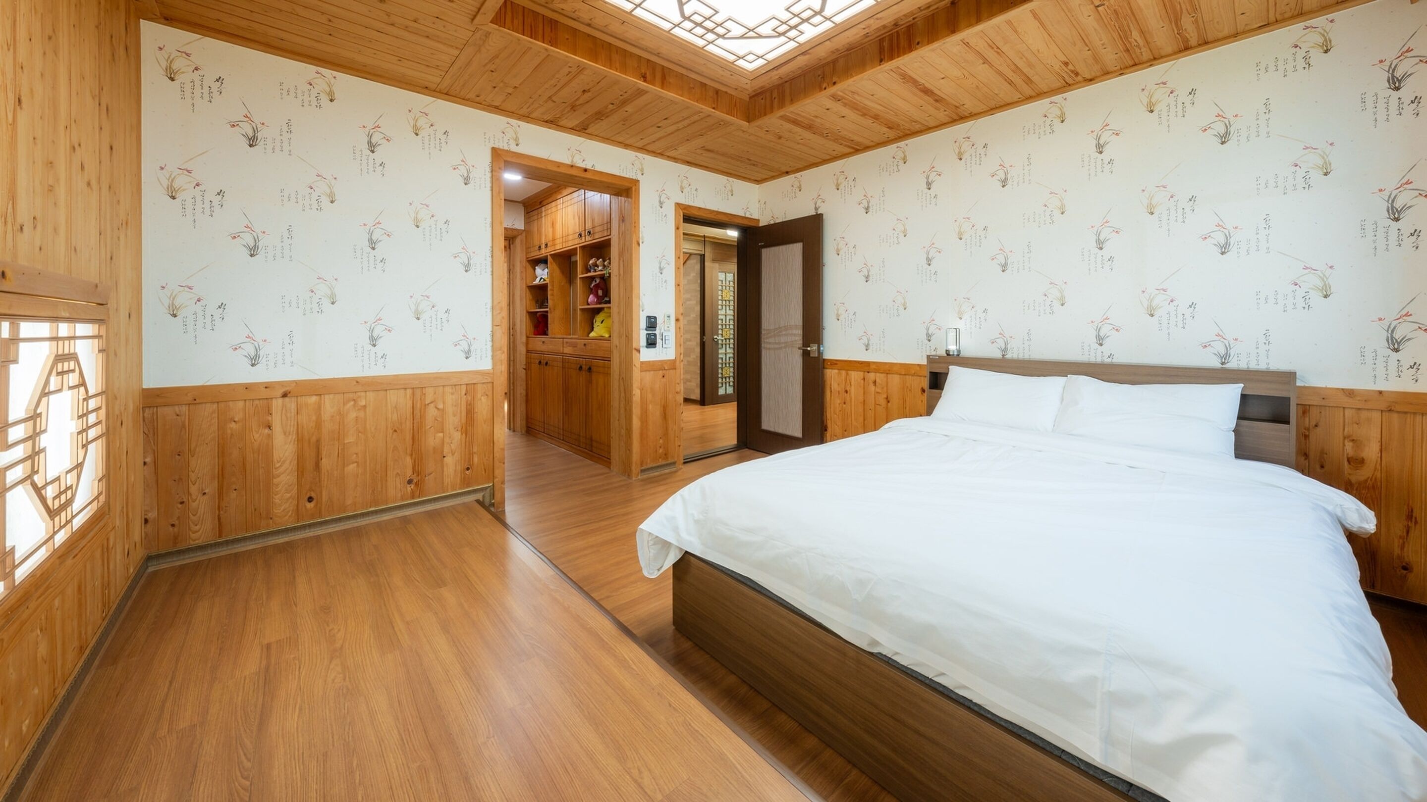A wooden room with a bed, wooden walls, and a skylight.
