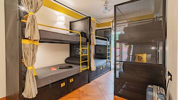 Ein Schlafsaalzimmer mit Etagenbetten, einem Schreibtisch und einem Koffer.