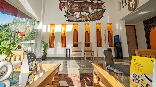 A modern lobby with a large ship decoration, wooden furniture, and a laptop on a table. - The Hosteller Goa, Old Goa (Panaji)