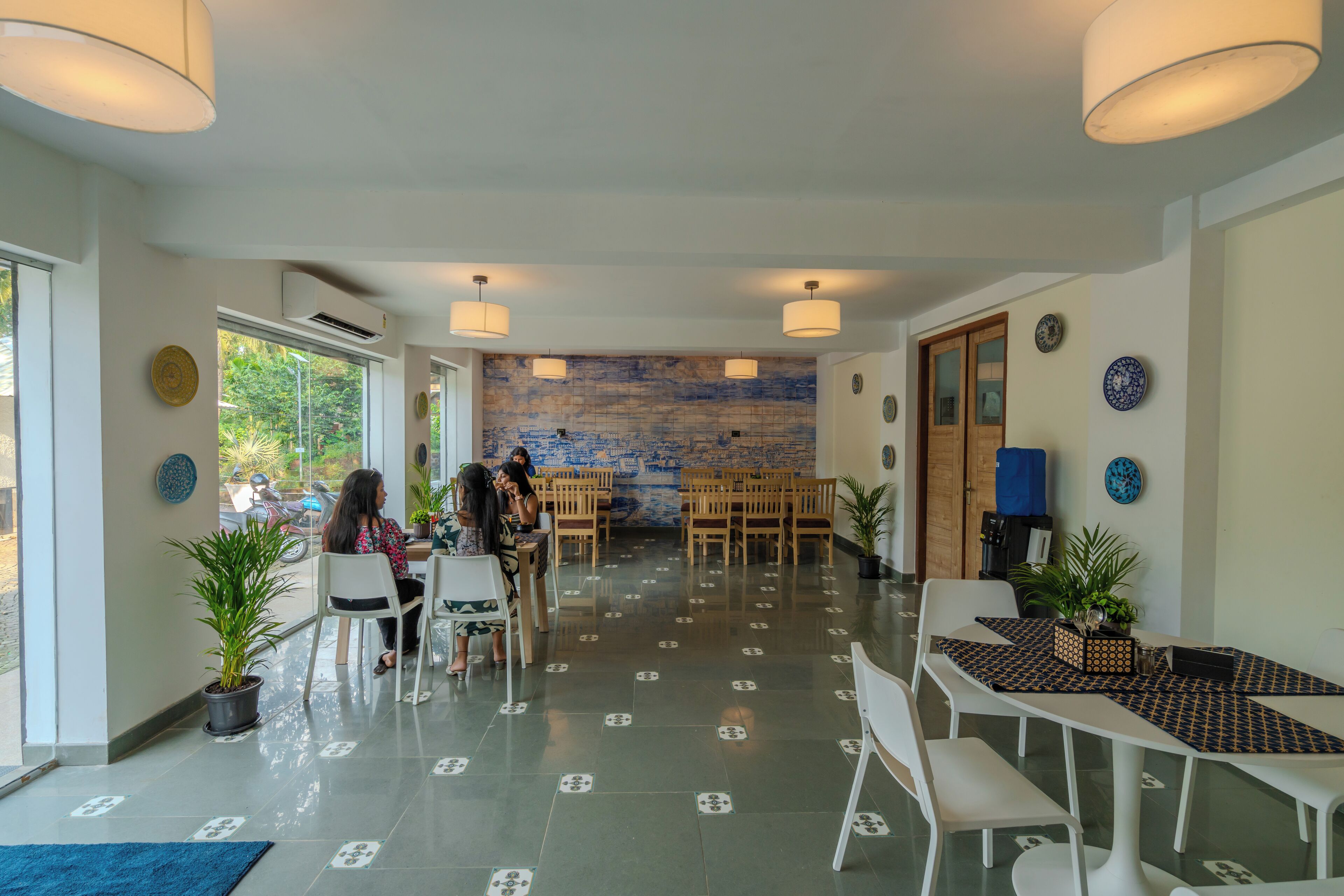 A spacious indoor area with multiple tables and chairs, a tiled floor, and a wall with a blue pattern.