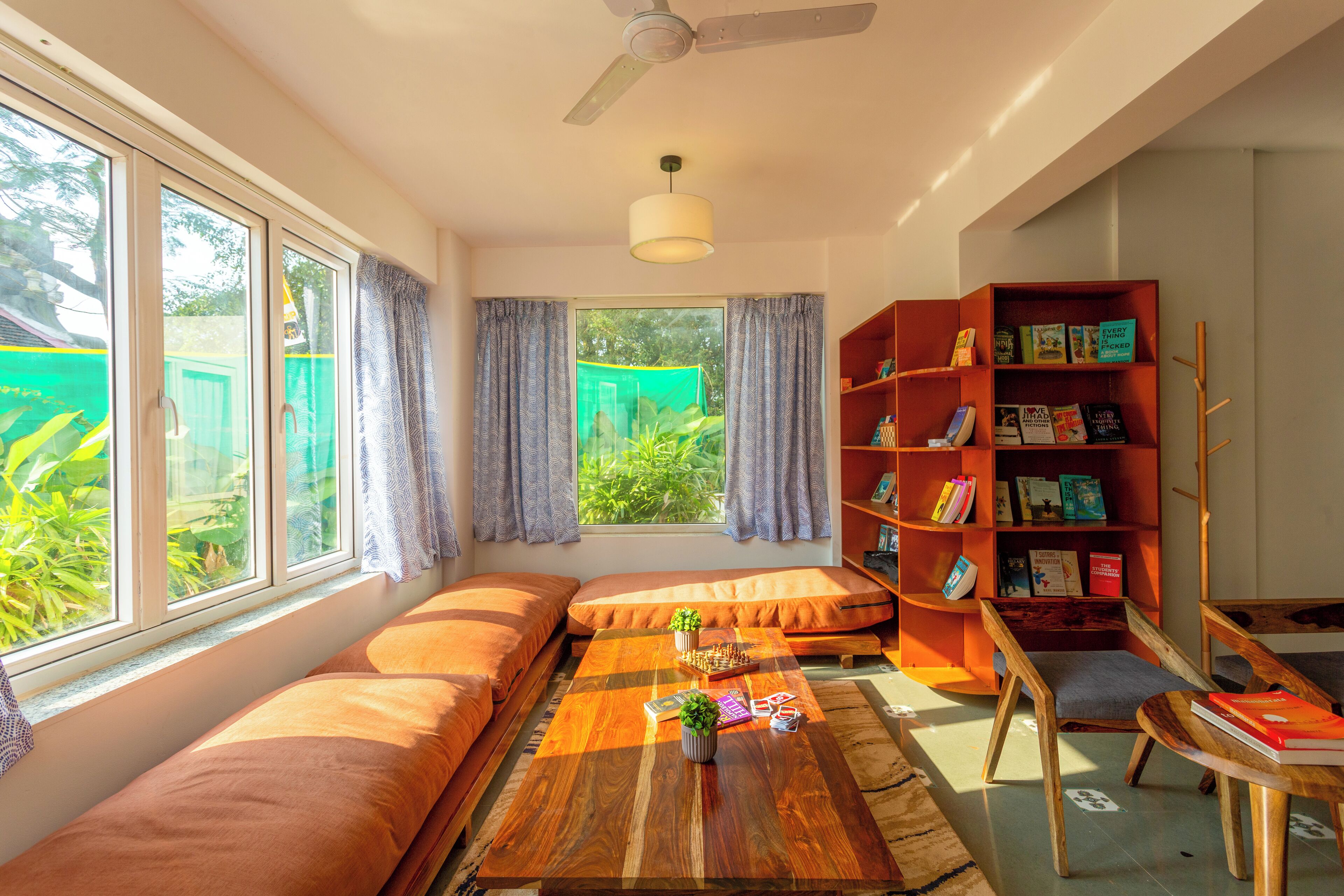A cozy room with a sofa, a wooden coffee table, a bookshelf, and a window with curtains.