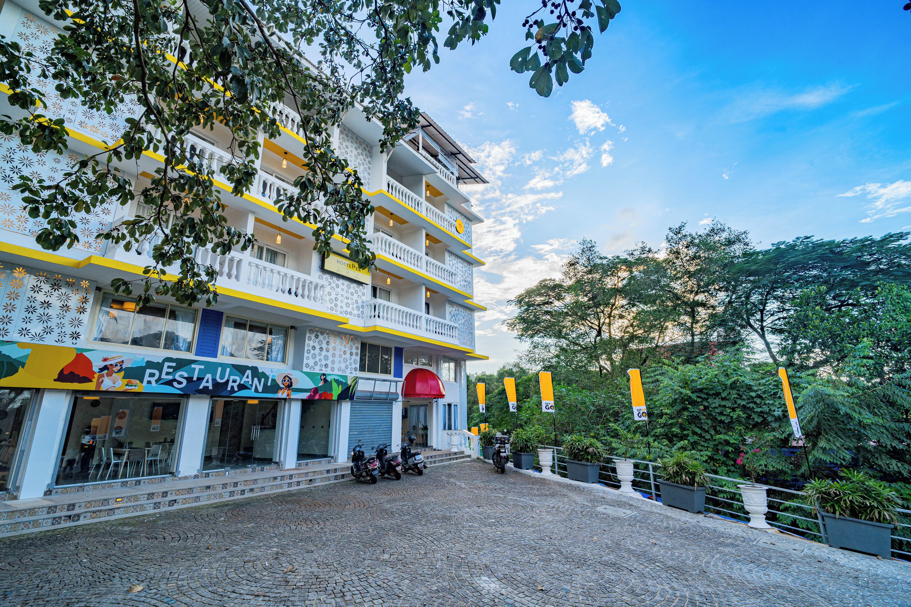 A multi-story building with a restaurant on the ground floor, balconies, and potted plants.