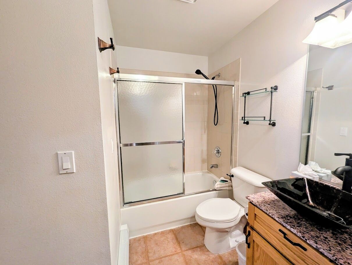 A bathroom with a glass-enclosed shower, a toilet, and a vanity with a sink.
