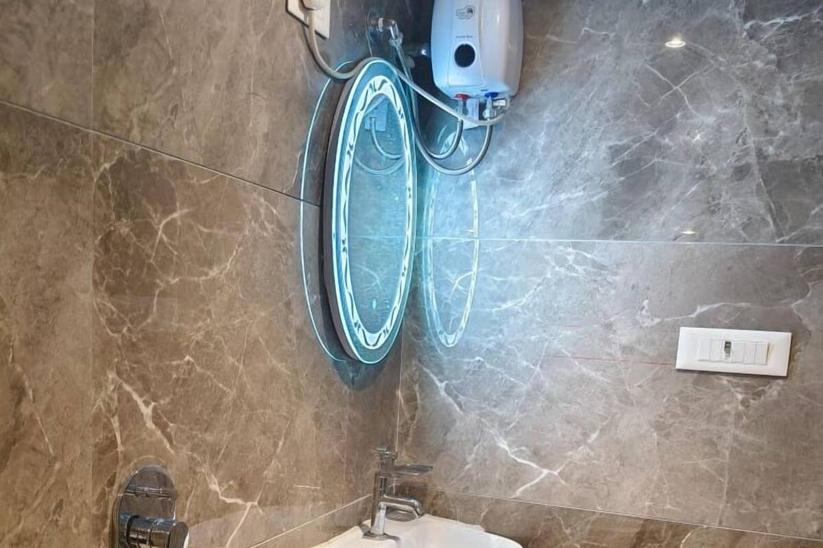Une salle de bain avec un mur en marbre, un lavabo fixé au mur, un porte-serviettes et un sèche-mains.