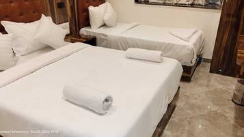 A hotel room with two beds, each with white linens and pillows, and a wooden headboard.