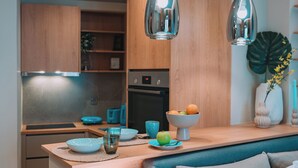 Eine moderne Küche mit Holzausstattung, einem eingebauten Backofen und einem Essbereich mit einem blauen Sofa.