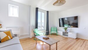 A modern living room with a sofa, two striped chairs, a coffee table, a TV, and a large window with curtains. - Apartments in Champigny-Sur-Marne - 30 minutes from Disneyland (Champigny-sur-Marne)