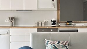 Een moderne keuken met witte kastjes, een magnetron en een koffiezetapparaat.