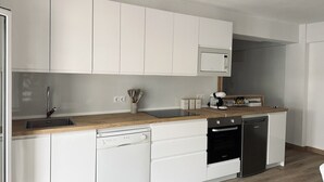 Een moderne keuken met witte kasten, een houten aanrecht, een inbouwoven en een vaatwasser.