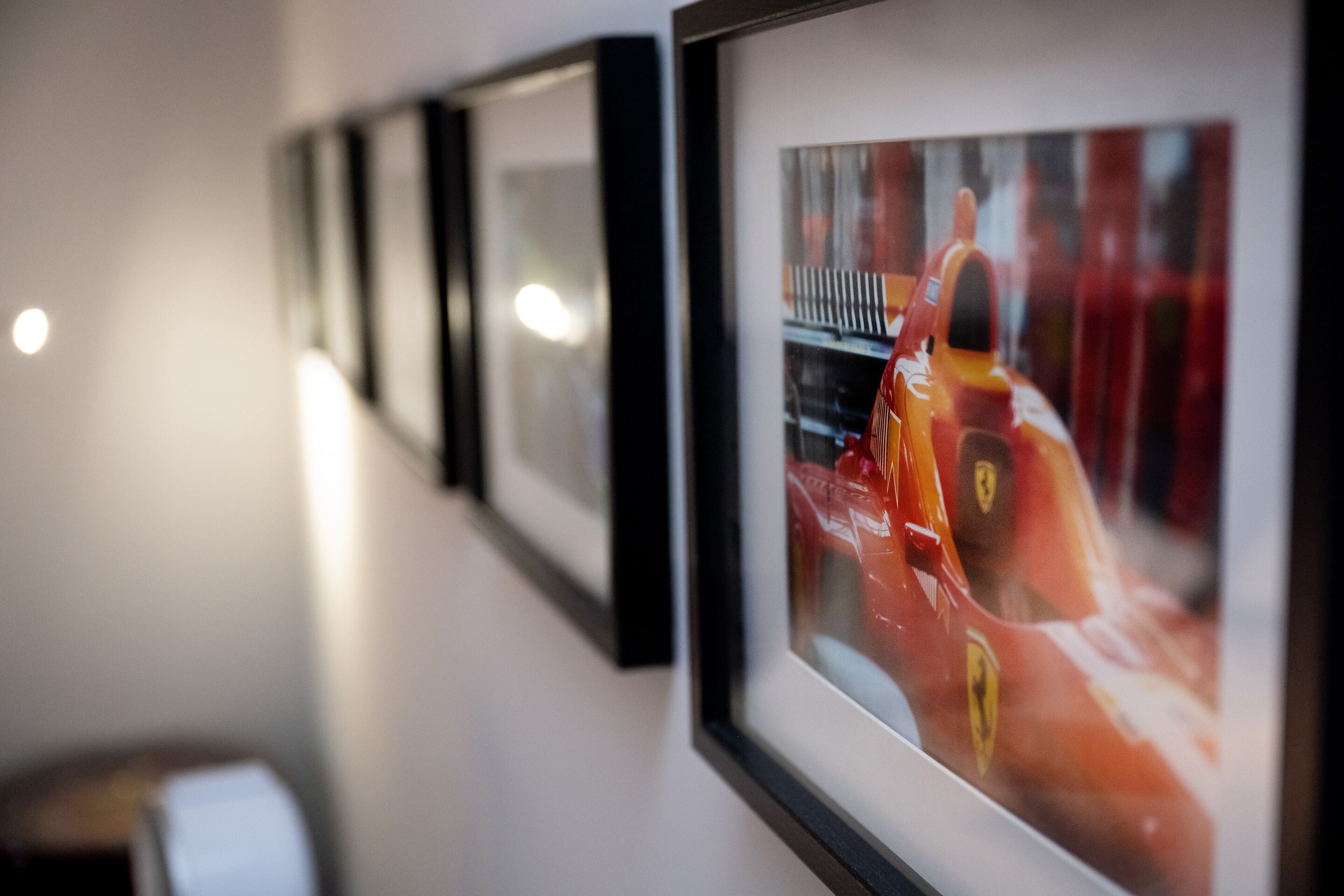 A series of framed pictures on a wall, including a prominent Ferrari racing car.