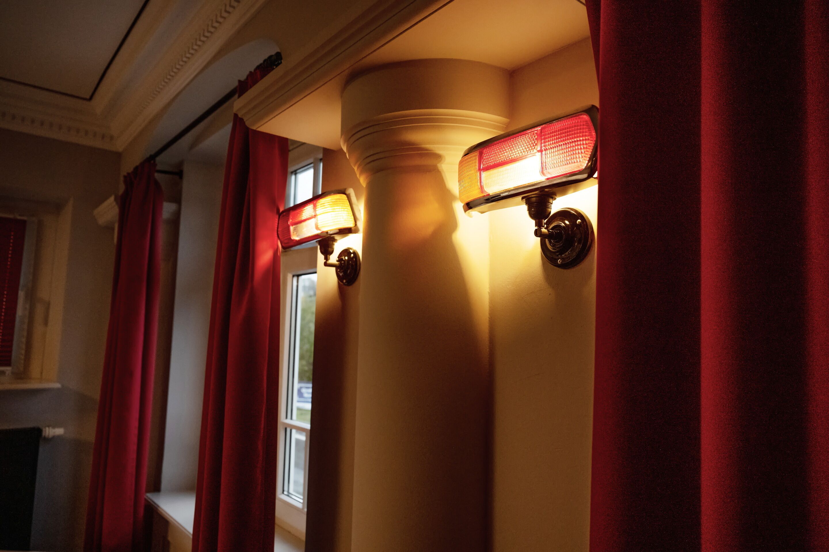 A corridor with red curtains and wall-mounted lights.