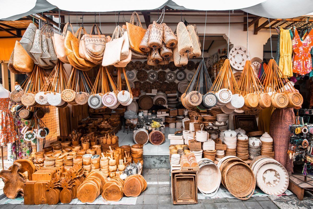 A market stall with various woven baskets, wooden utensils, and hanging bags.