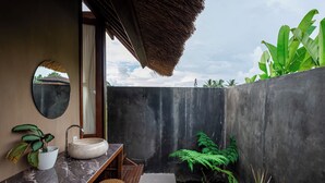 A bathroom with a marble sink, a mirror, and a wooden bench. - Pondok Mawas (Ubud)