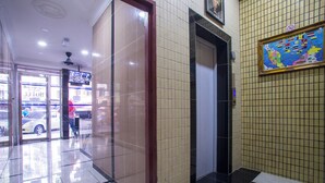 A hotel lobby with a glass door entrance, a tiled wall with a map, and a black and beige patterned floor. - MK Inn Hotel (Kuala Lumpur)