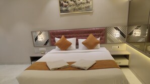 Una habitación de hotel moderna con una cama grande, un cabecero con diseño acolchado y un cuadro sobre la cama.