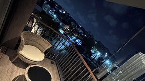 A balcony with wicker furniture and a city view at night. - Charming 1-bedroom condo at The Diamond In City, Cantonments Accra. Luxe-Modern (Accra)