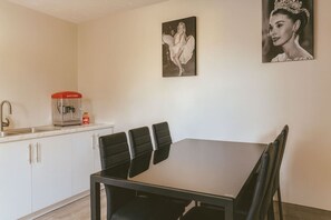 Un coin repas avec une table et des chaises, une machine à café et un tableau accroché au mur.