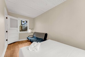 Une chambre à coucher avec un lit, un banc, une fenêtre et une porte.