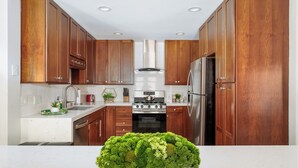 Una cocina moderna con armarios de madera, electrodomésticos de acero inoxidable y una encimera de mármol.
