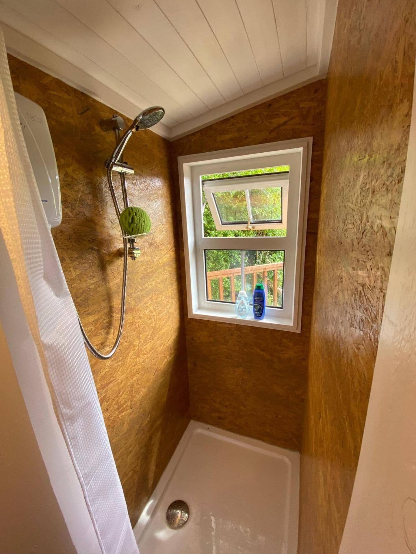 Un baño pequeño con ducha, ventana y puerta.