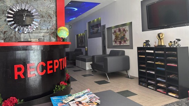 Zona de recepción con un reloj, un globo terráqueo y revistas sobre una mesa.