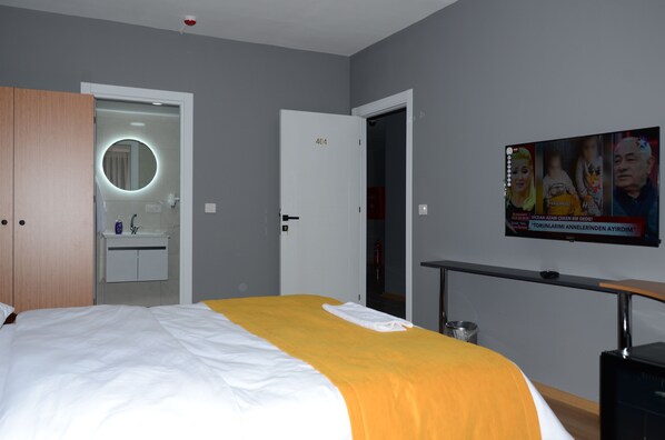 A hotel room with a bed, a bathroom with a mirror, and a TV on the wall. - By Karam Otel (Istanbul)