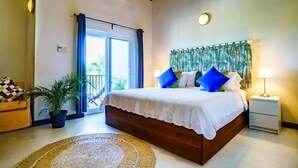 Une chambre à coucher avec un lit, une table de chevet, une plante en pot, un ventilateur de plafond et une vue sur l’extérieur.