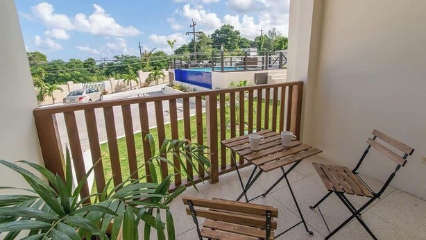 A balcony with a wooden railing, a small table with a cup, and a chair.