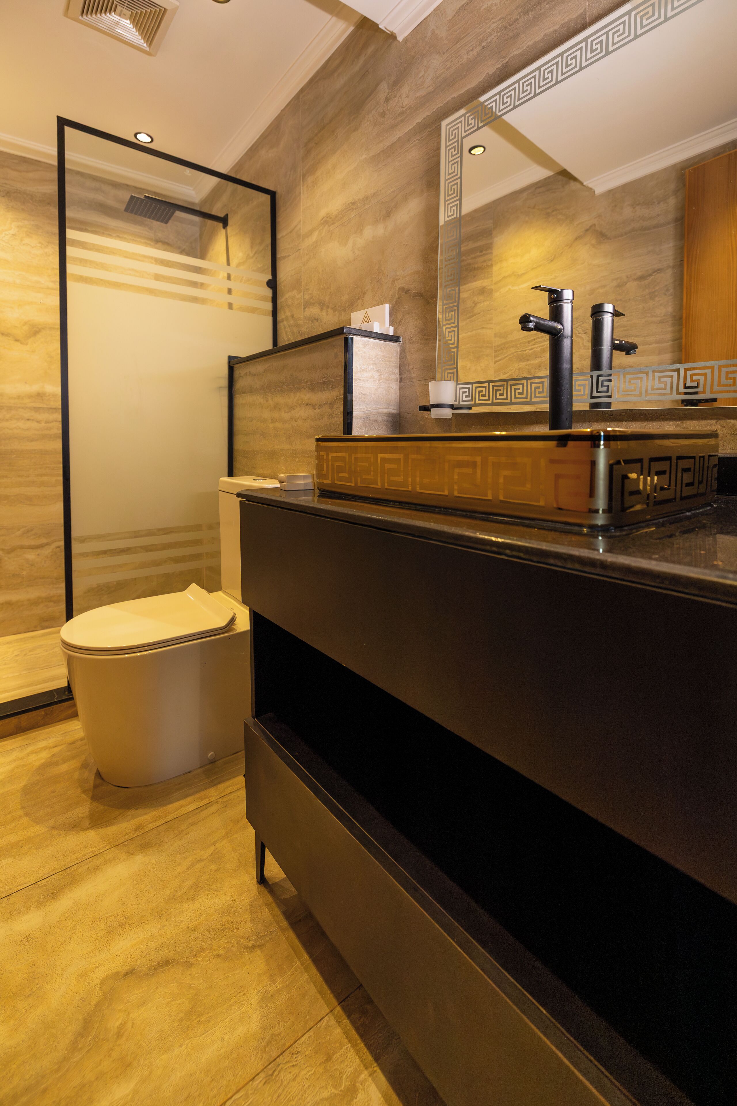 A modern bathroom with a marble floor, a black vanity with a mirror, and a toilet.