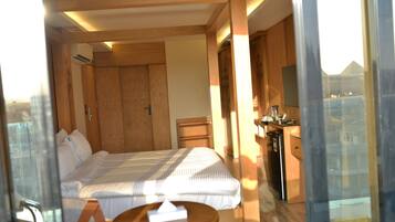 A hotel room with a bed, bedside table, and a small kitchenette area.